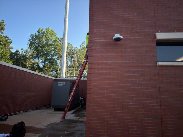 Surveillance camera mounted high on a brick exterior wall