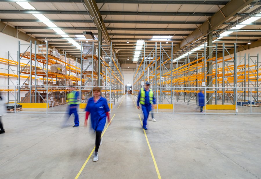 Workers walking a warehouse aisle between tall racking